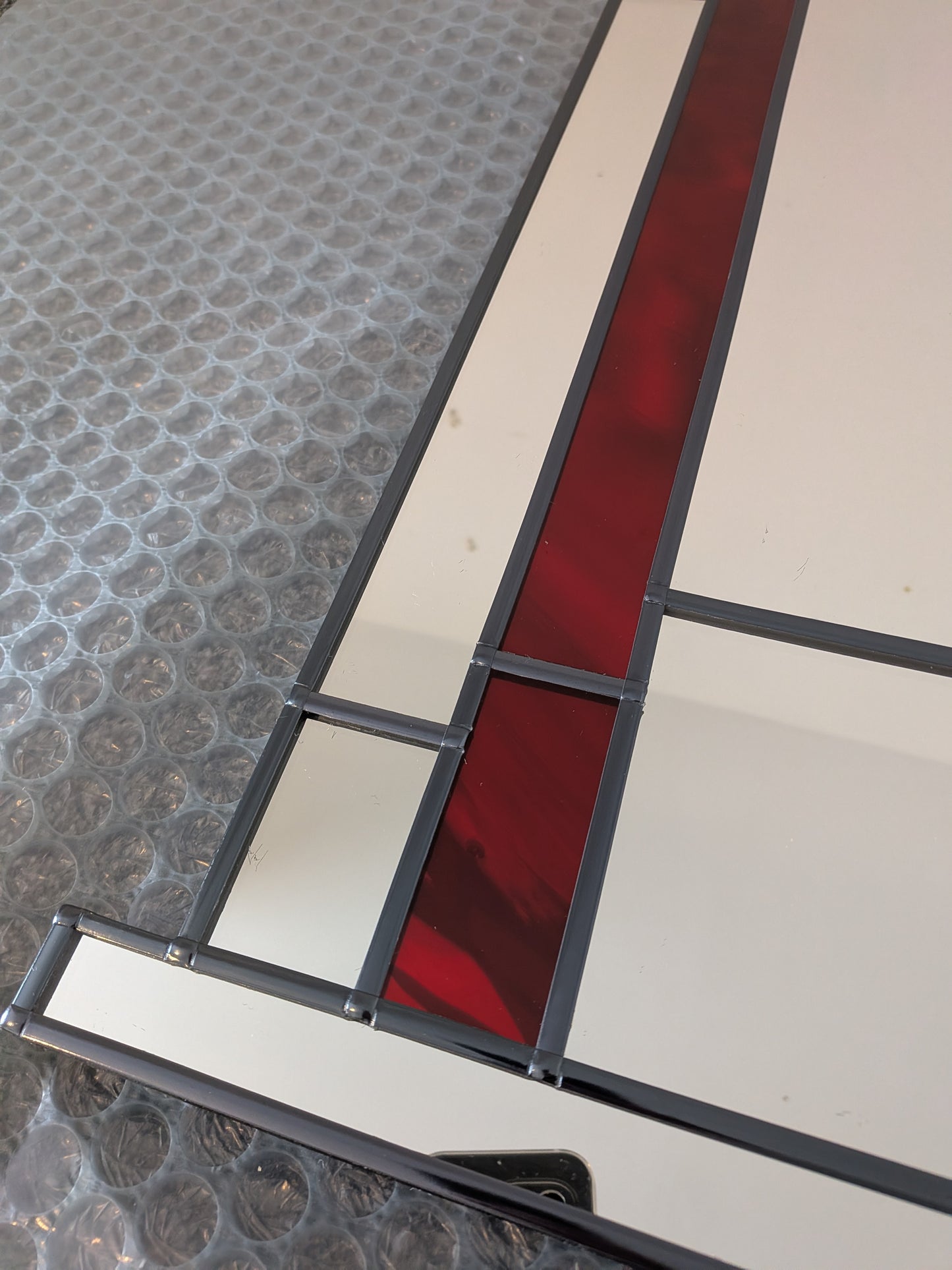 Stained glass panel with red and white design on a textured surface
