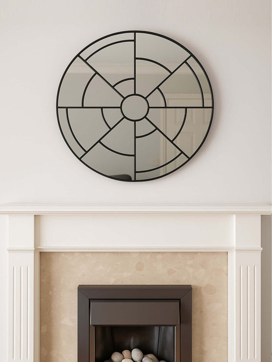 Decorative round mirror with geometric design above a fireplace.