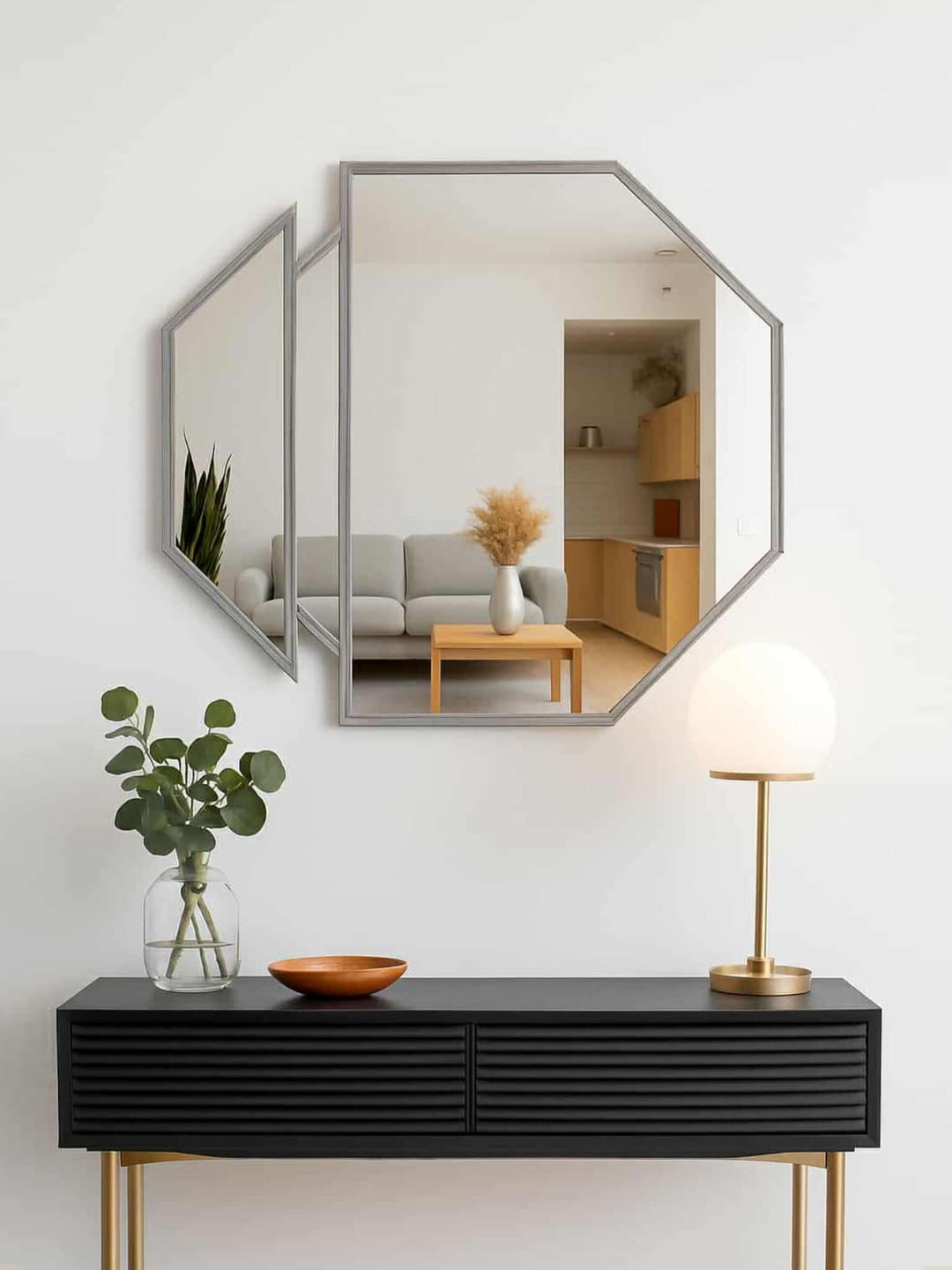 Hexagonal mirror on a white wall above a black console table with decorative items.
