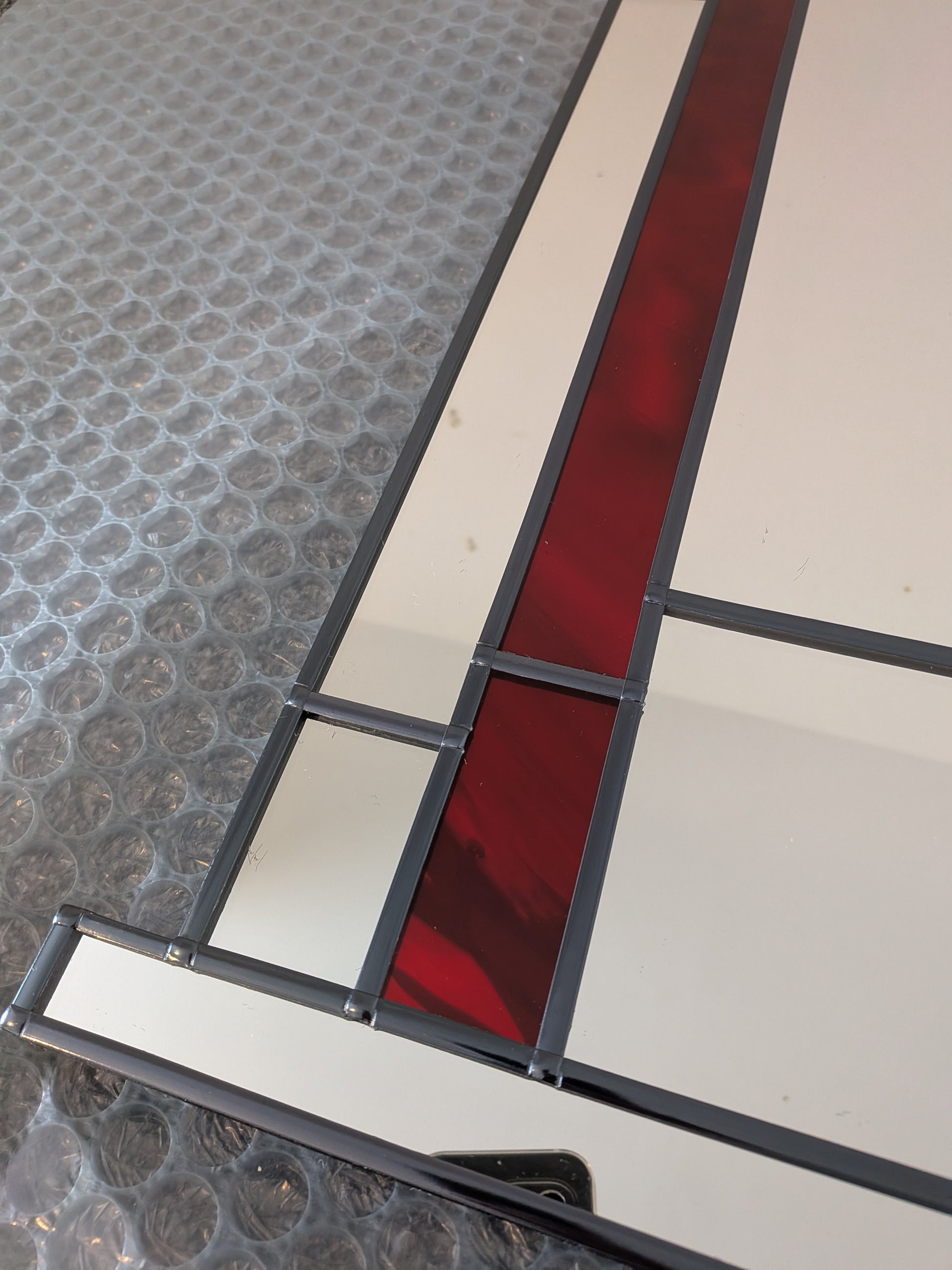 Stained glass panel with red and white design on a textured surface