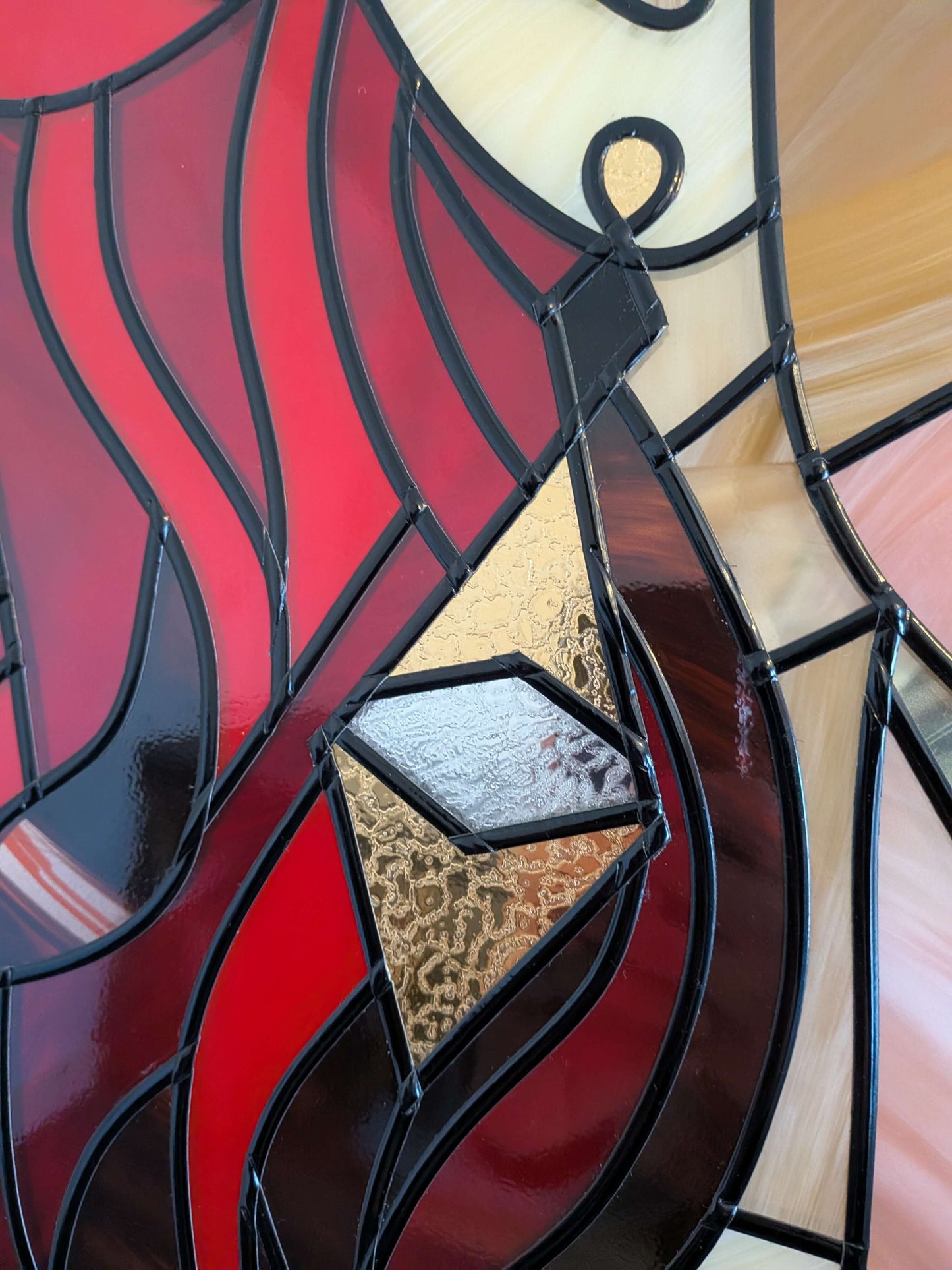 Close-up of a stained glass panel with red, black, and gold colors.