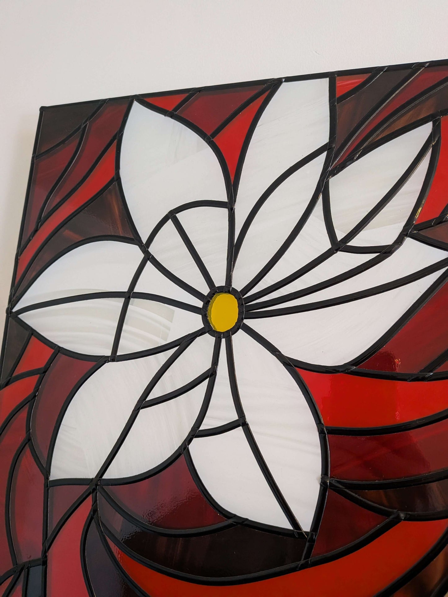 Stained glass panel with a white flower design on a red background