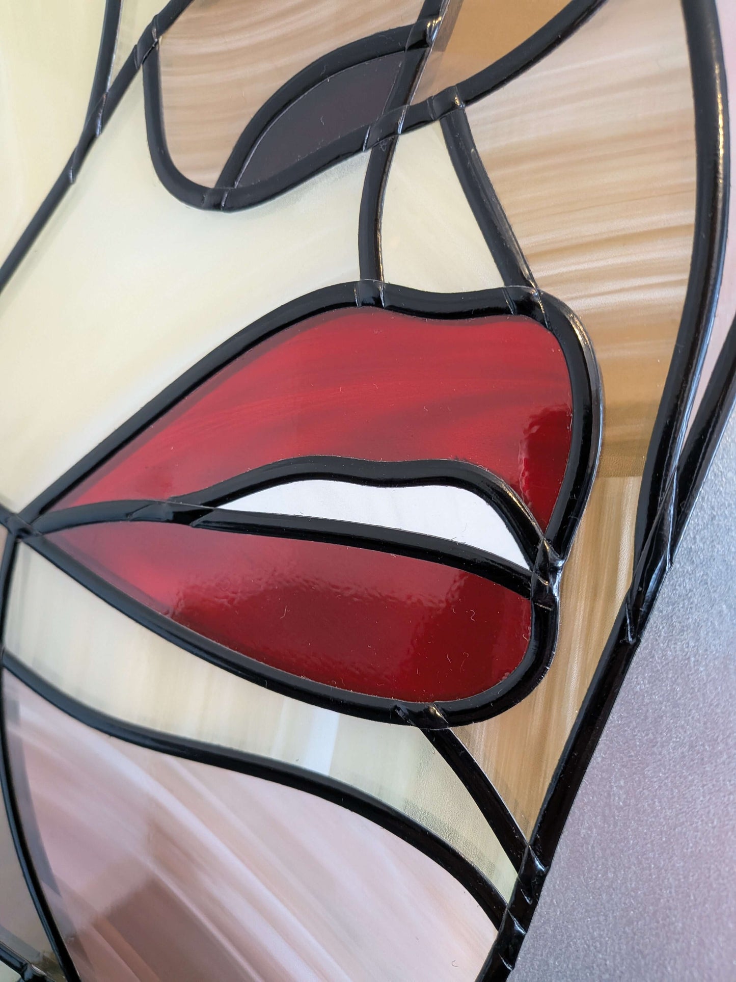 Stained glass panel with red lips design on a wooden surface