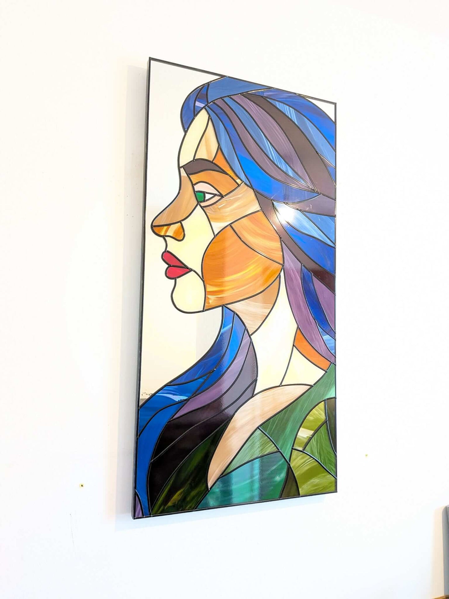 Modern stained glass style wall art featuring a colourful abstract portrait of a woman in profile. This vertical framed artwork showcases bold geometric shapes in rich blue, purple, green, and warm amber tones, with striking red lips and a green eye. The contemporary cubist-inspired design adds elegance and sophistication to living rooms, bedrooms, offices, or gallery walls. A vibrant statement piece perfect for modern home décor, art collectors, and unique gift ideas.